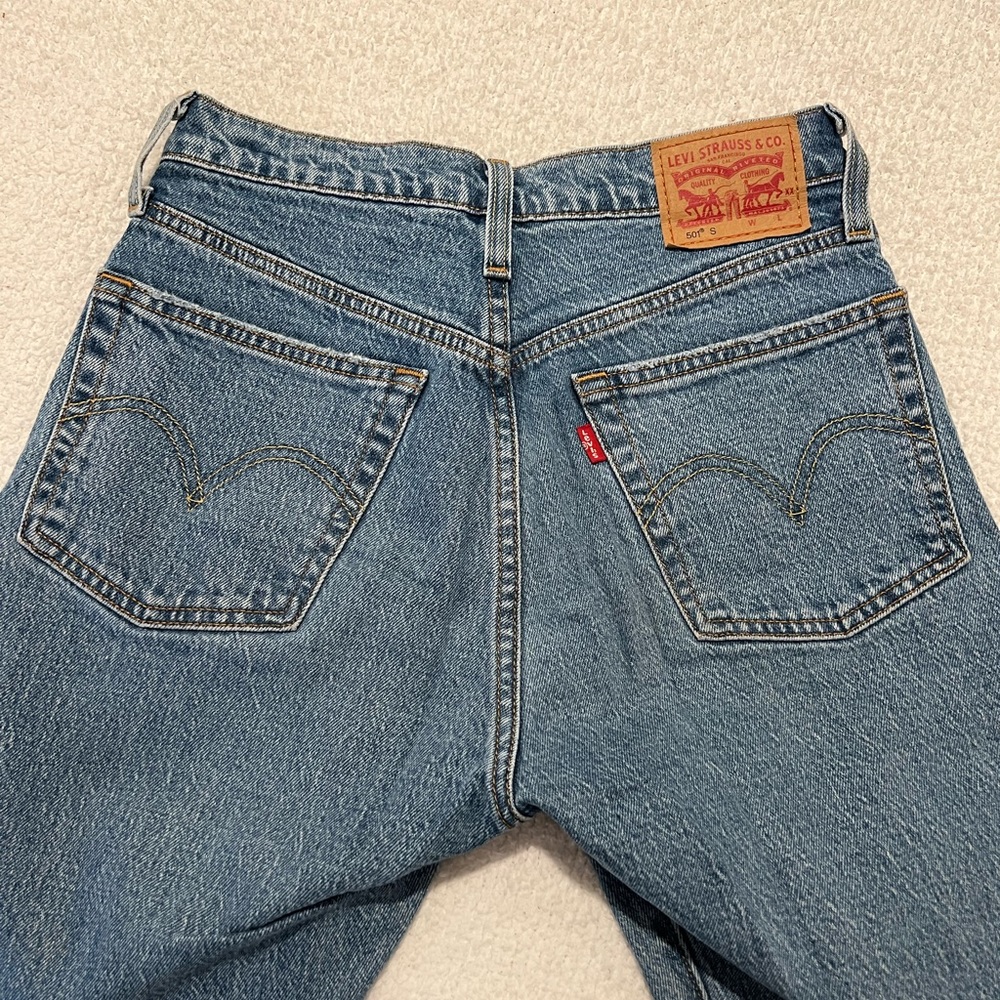 MEDIUM WASH LEVI 501’s WITH ONE KNEE HOLE AND FRAYED BOTTOMS